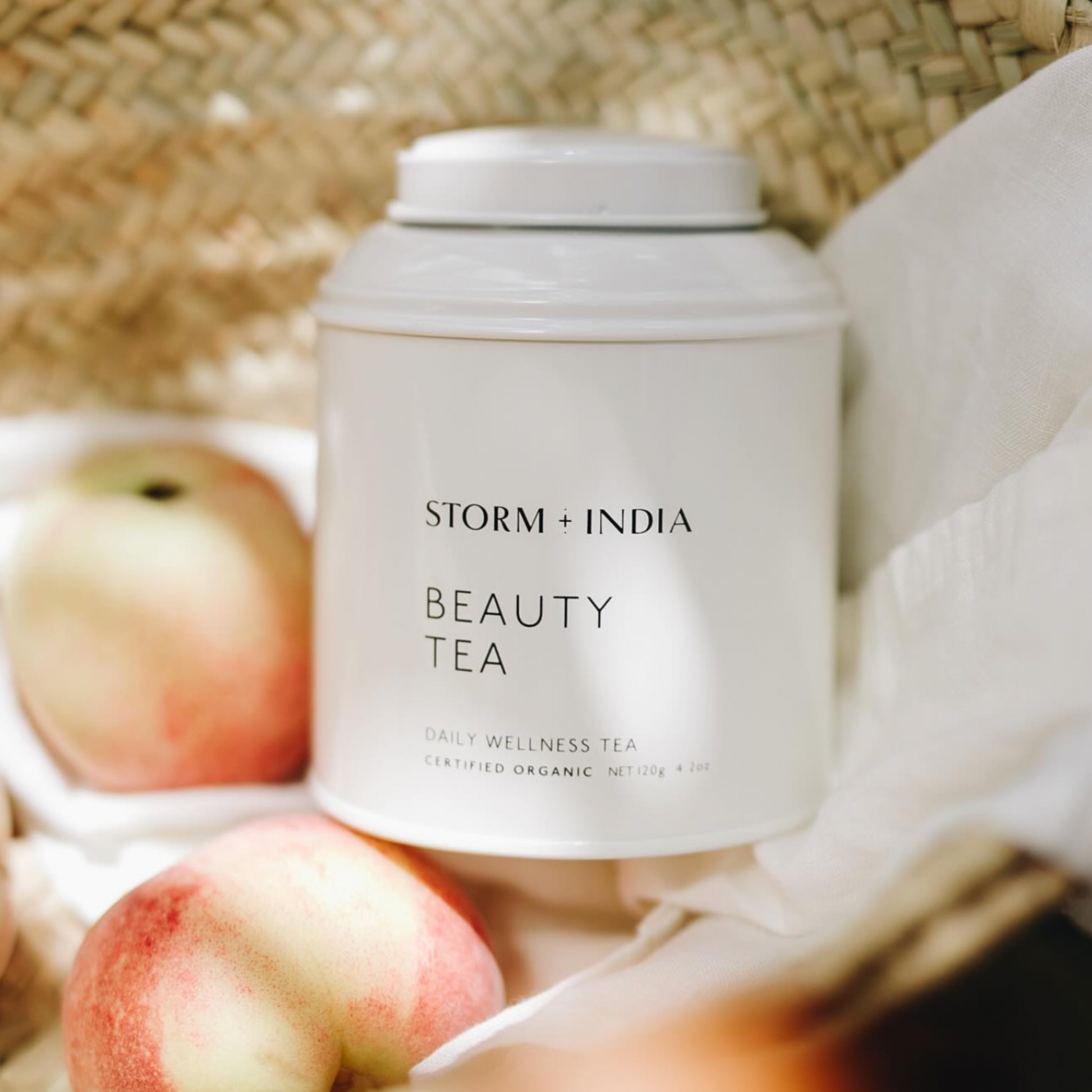 Storm and India Loose Leaf Tea in Tin 100g Beauty Tea in woven basket with table cloth and peaches 