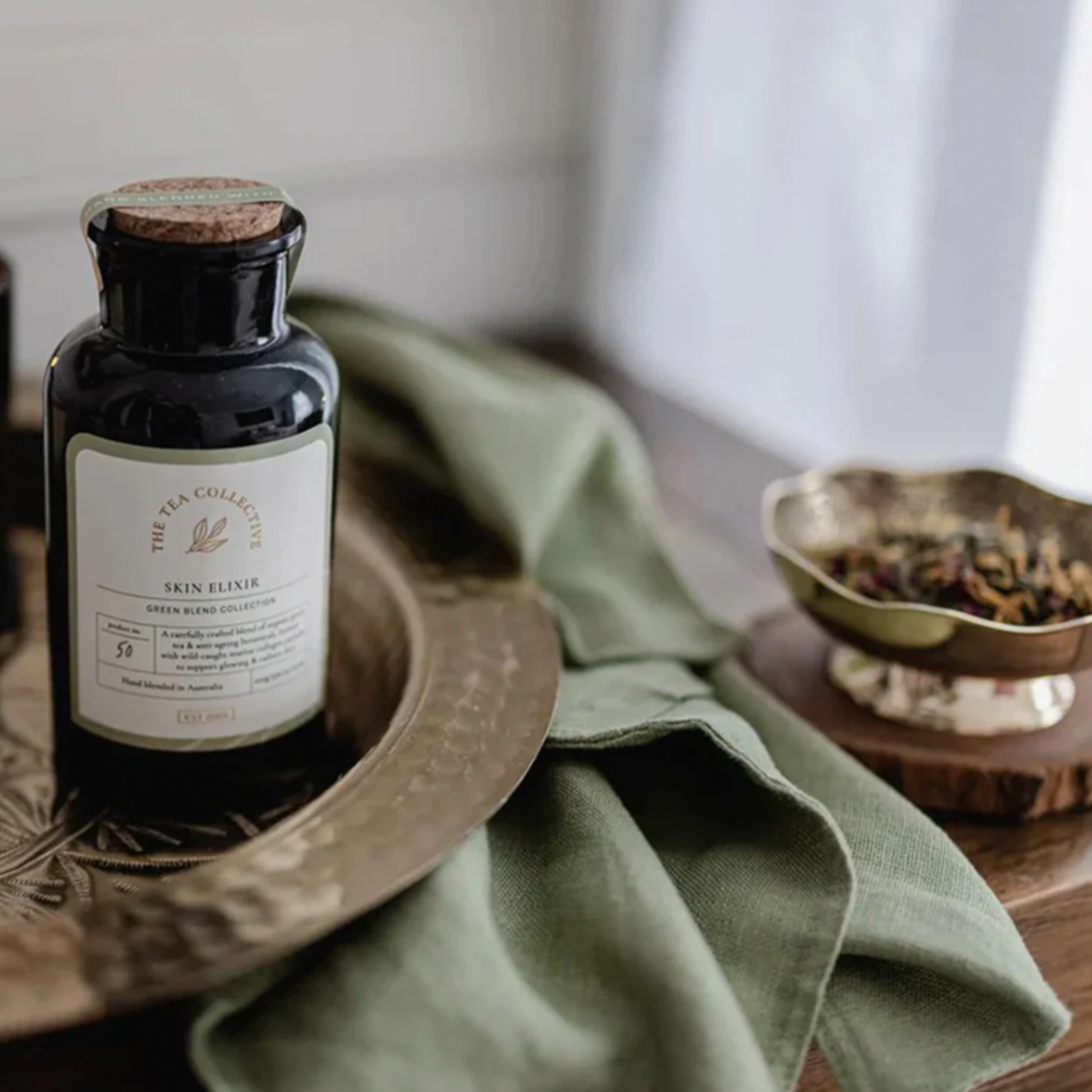 The Tea Collective loose leaf skin elixir on display on table wiyh green table cloth