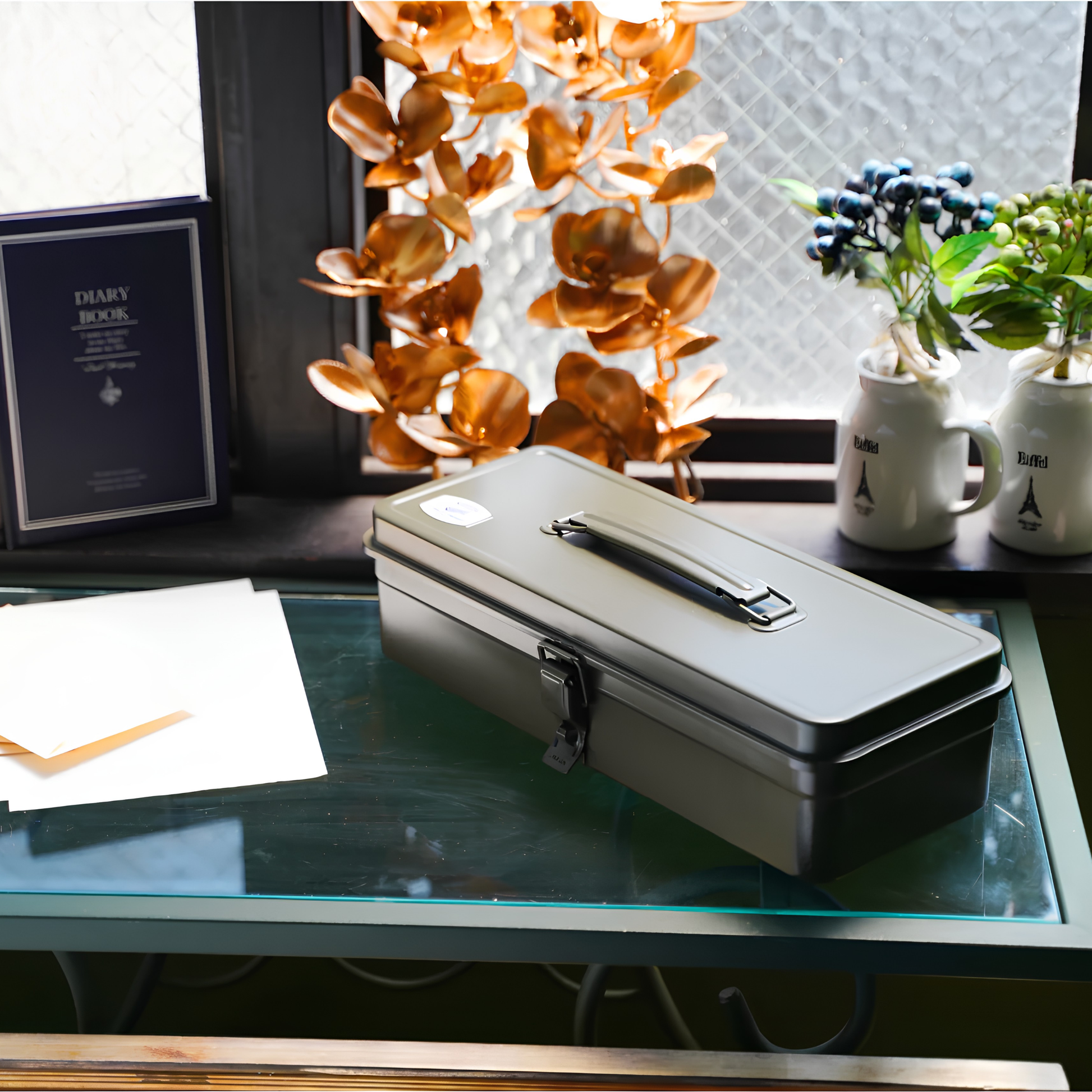Toyo Toolbox Trunk Shape T-320 Moss Green on a glass table, it's crafted from a single pressed steel, smooth and rounded design with matte texture that's gentle on hands.