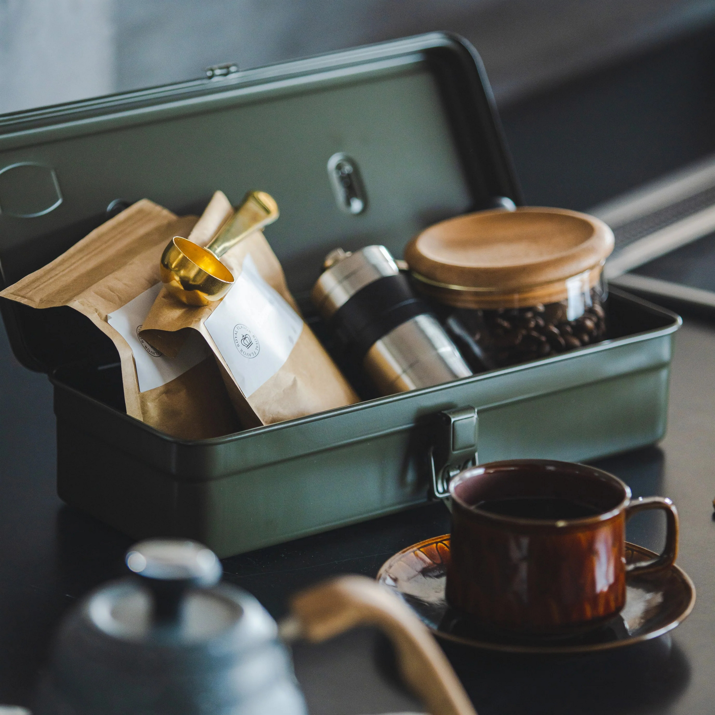 Showing coffee making essentials inside the Toyo Toolbox Trunk Shape T-320 Moss Green crafted from a single pressed steel, smooth and rounded design with matte texture that's gentle on hands.