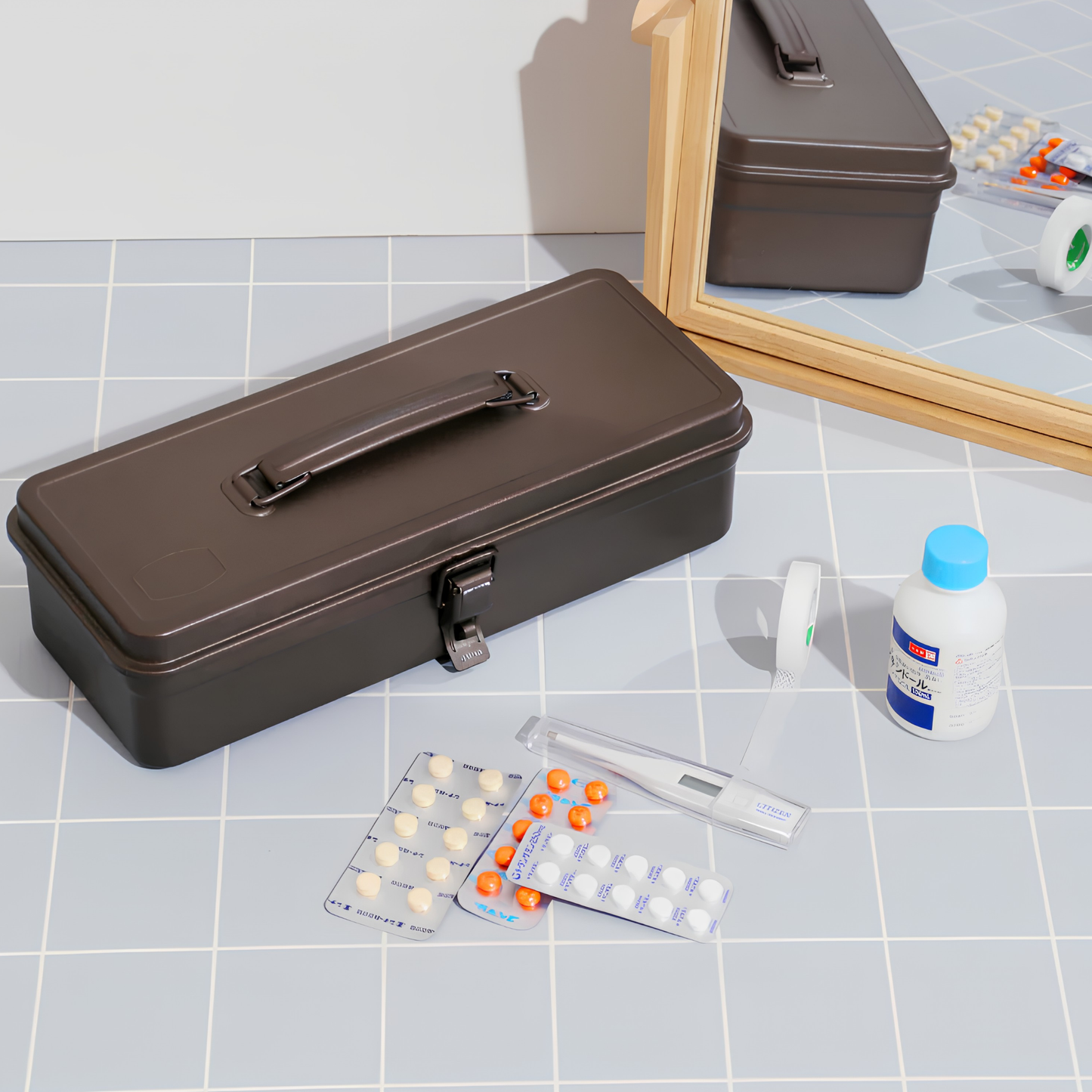 Showing medical essentials beside the Closed Toyo Toolbox Trunk Shape T-320 Titanium that is crafted from a single pressed steel, smooth and rounded design with matte texture that's gentle on hands.