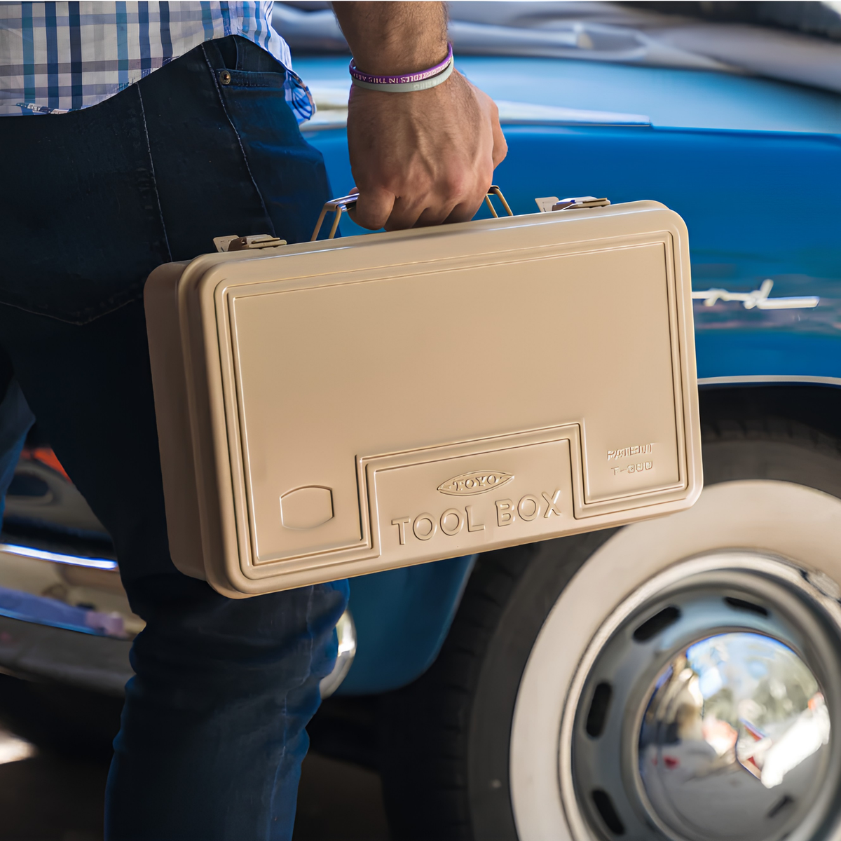 A man carrying the Toyo Toolbox Trunk Shape Toolbox T-360 Beige made from pressed steel plate, glossy with no sharp edges.