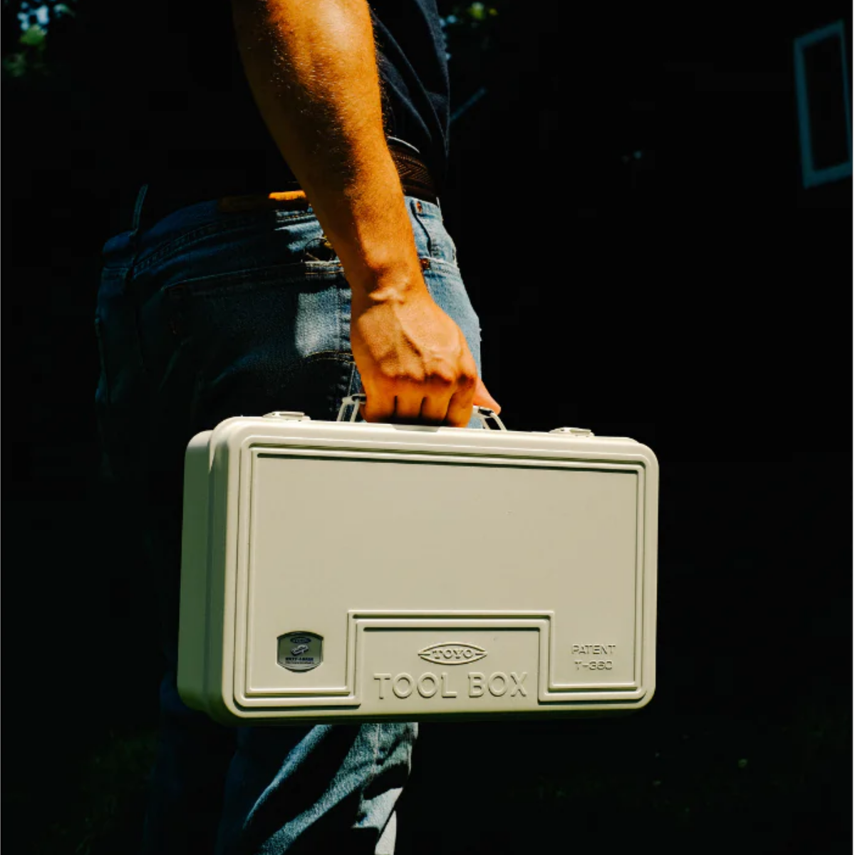 A man carrying the Toyo Toolbox Trunk Shape Toolbox T-360 White made from pressed steel plate, matte with no sharp edges.